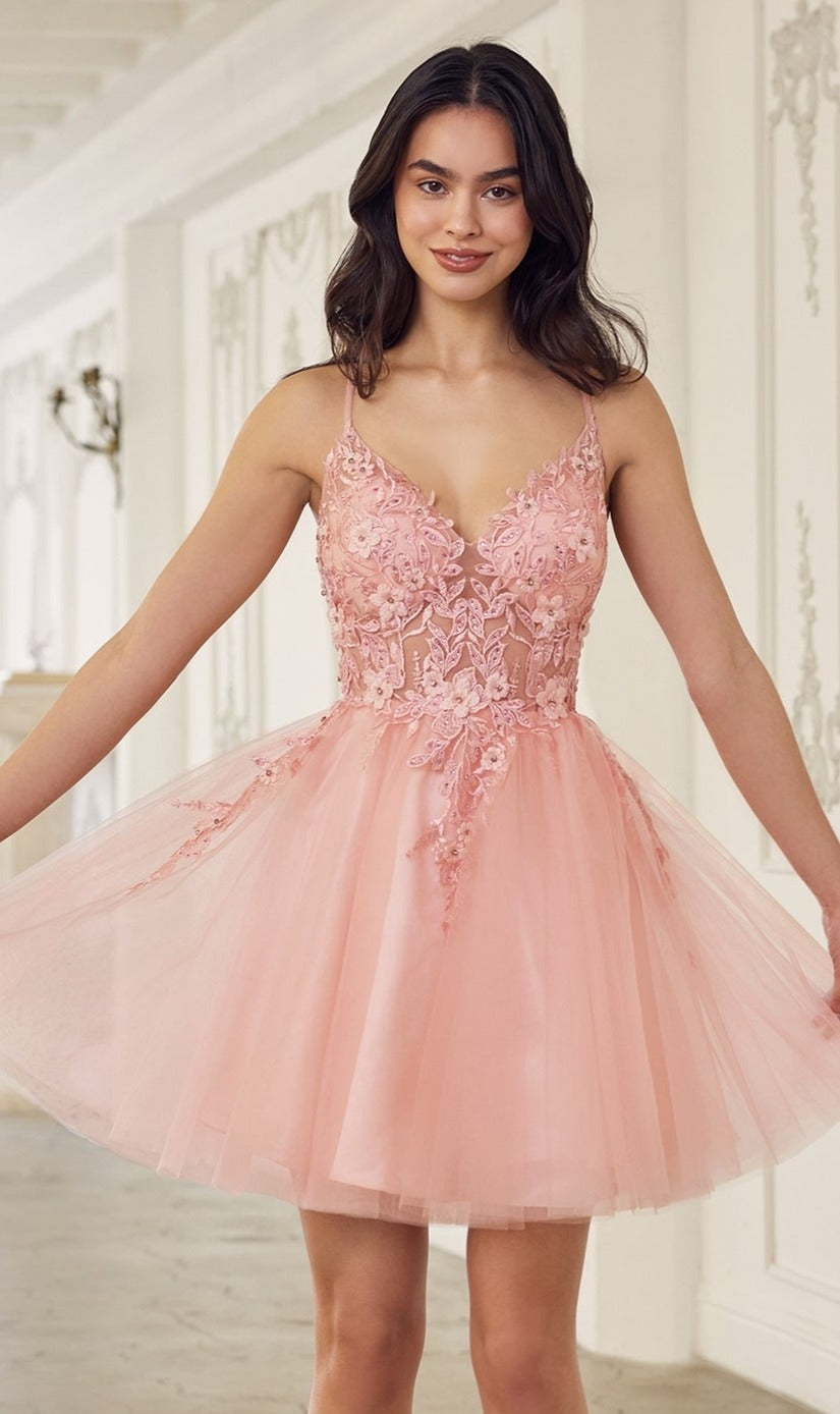 A woman stands indoors wearing the Short Babydoll Homecoming Dress: CLSF047, featuring a sleeveless pink tulle skirt and an embroidered lace bodice with delicate floral details and a fitted silhouette.